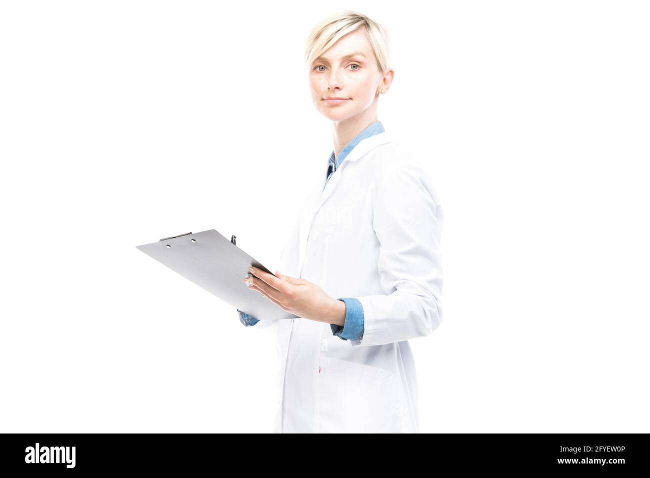 Portrait horizontal moyen de beau médecin caucasien portant un manteau blanc tenant le presse-papiers avec la carte médicale faisant des notes, fond blanc Banque D'Images