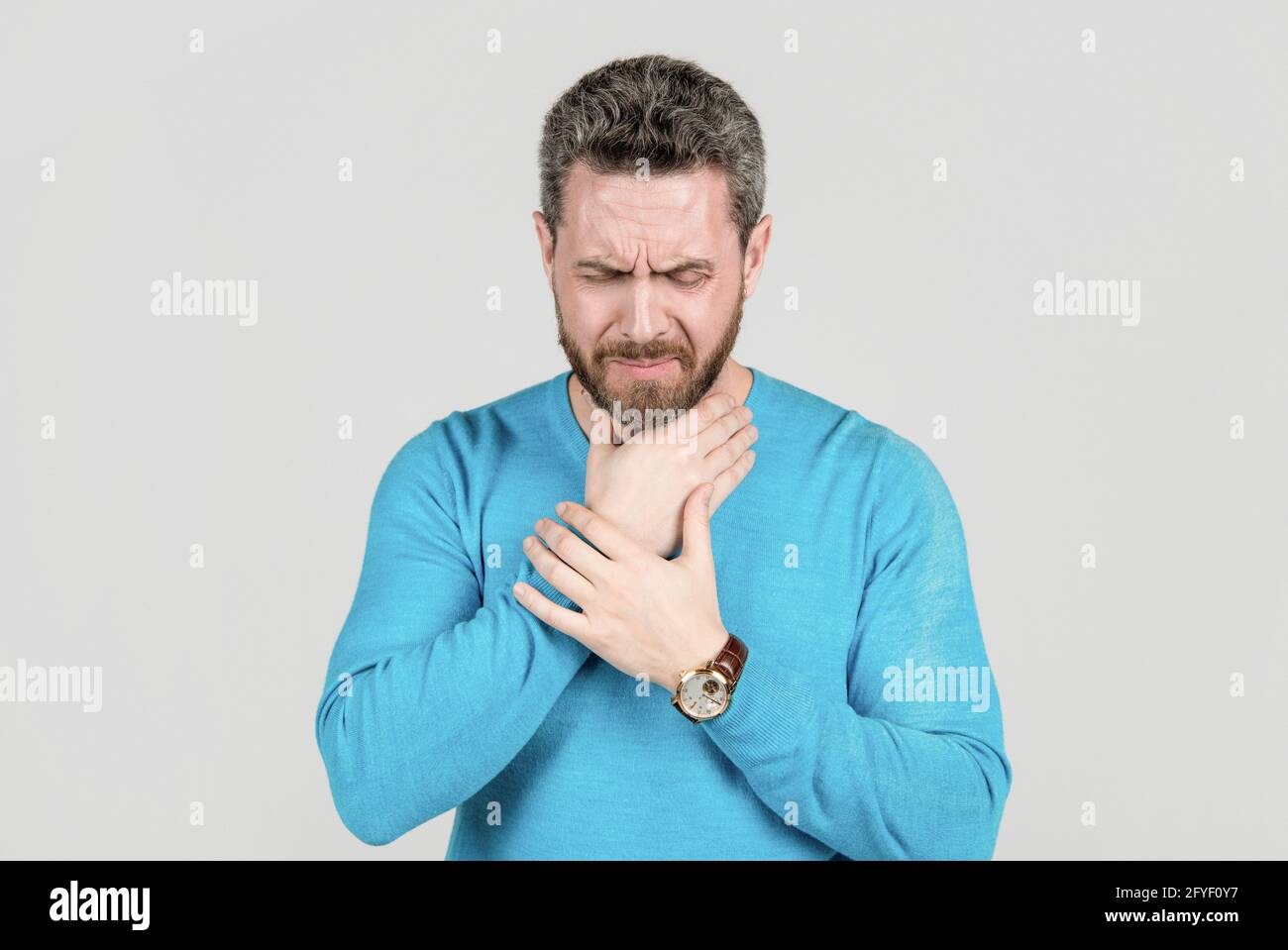 l'homme mature qui a la barbe souffre d'un mal de gorge sur fond gris, froid Banque D'Images