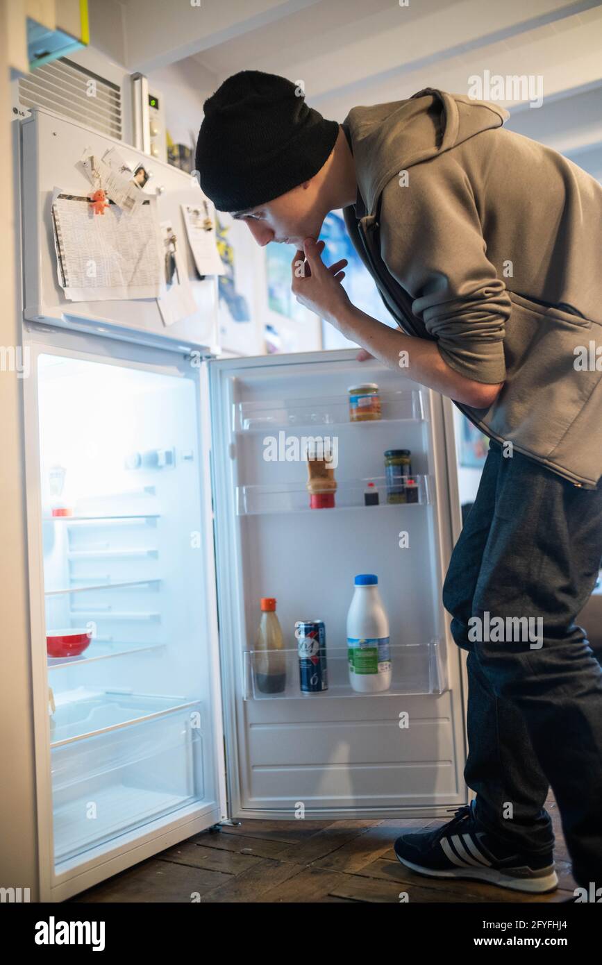 Jeune homme devant son réfrigérateur. Illustration de la précarité des jeunes, France. Banque D'Images