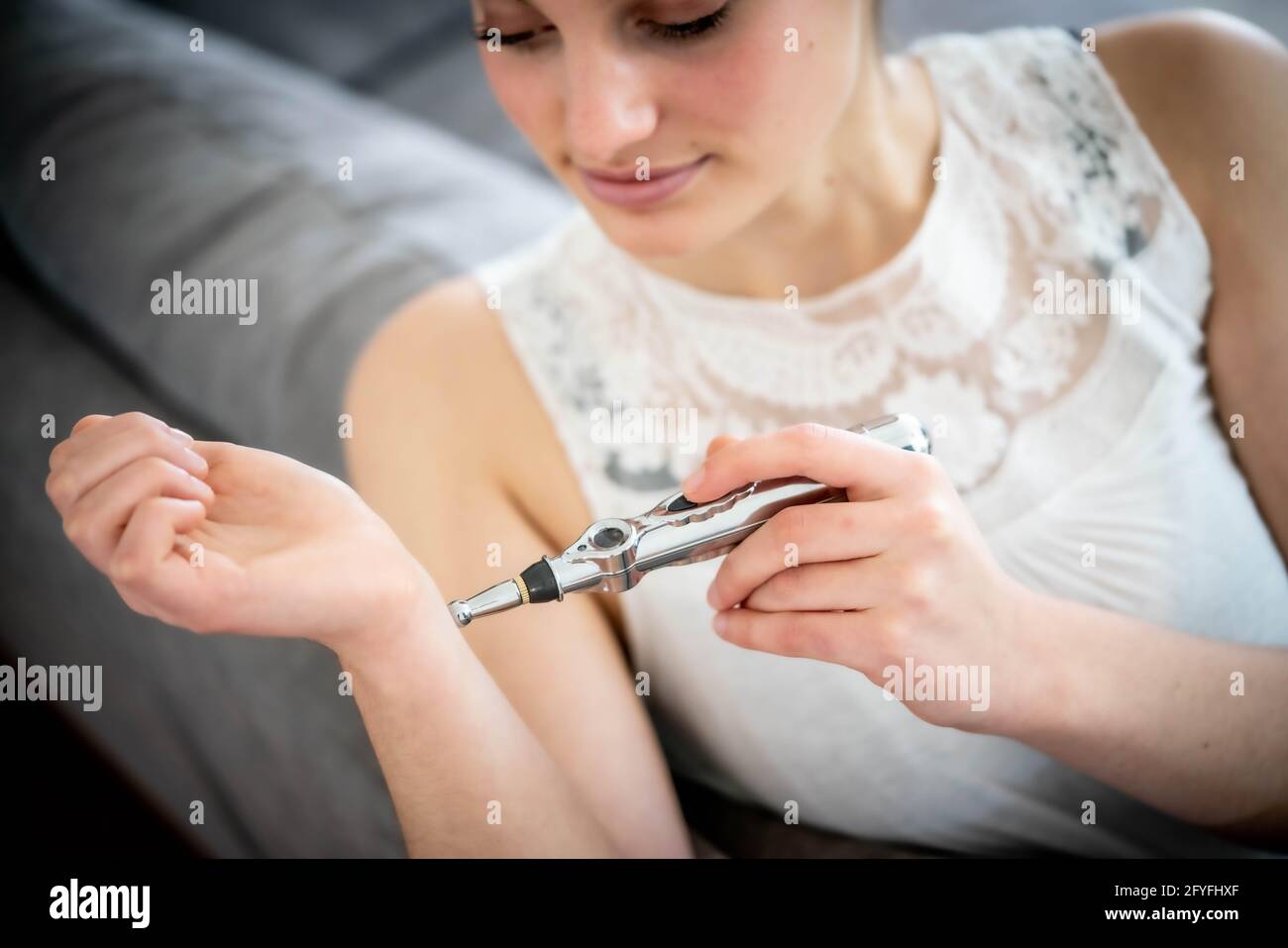 Femme utilisant le masseur électronique stylo d'acupuncture de l'énergie méridiens pour le soulagement de la douleur. Banque D'Images