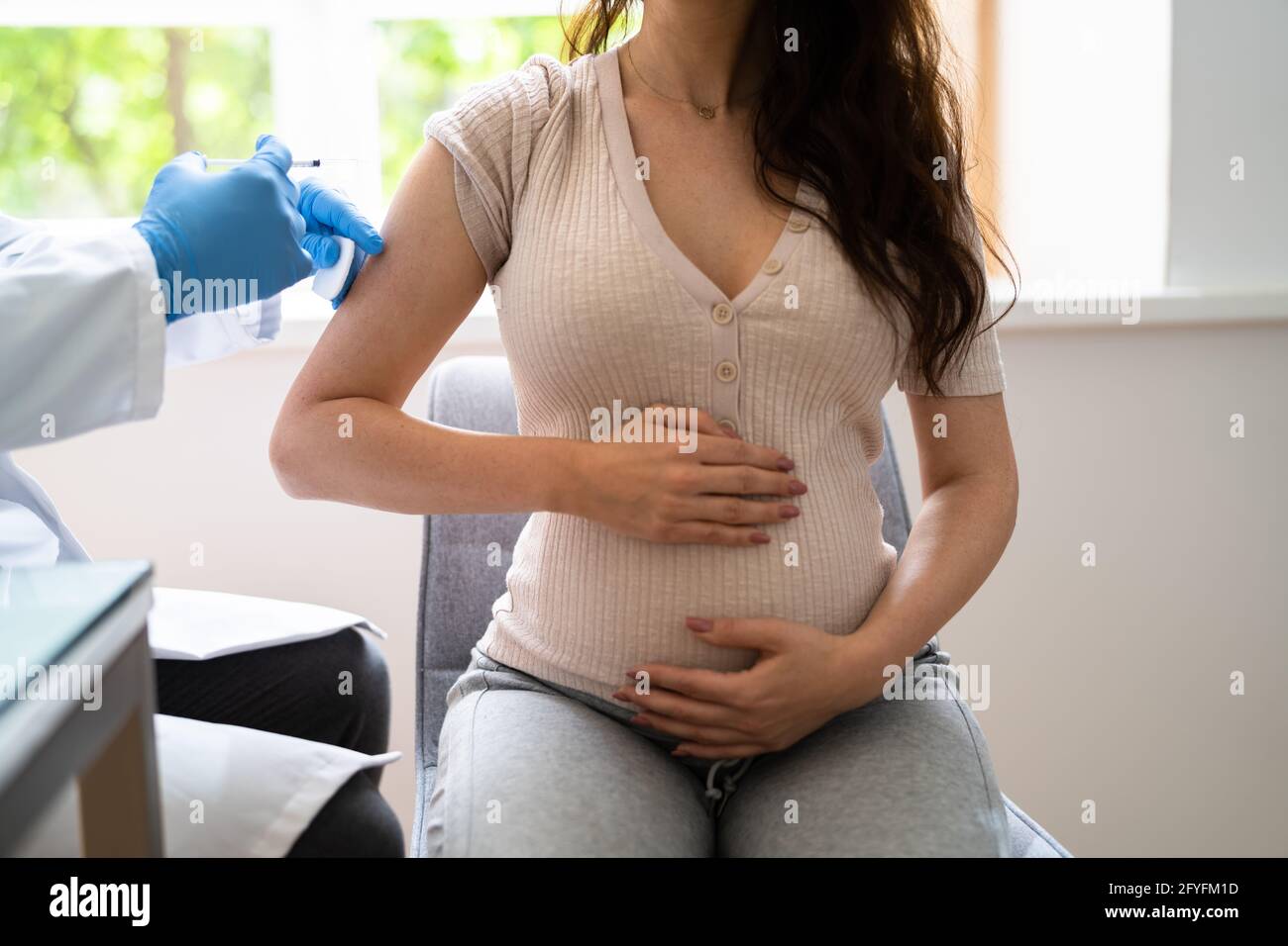 Médecin effectuant l'injection du vaccin Covid-19 à la femme enceinte patient Banque D'Images