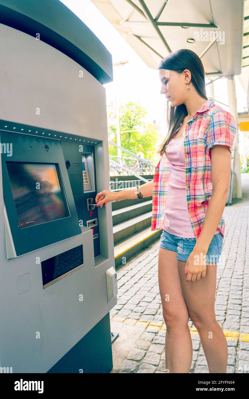 La jeune femme utilise un distributeur automatique pour les billets de transport Banque D'Images