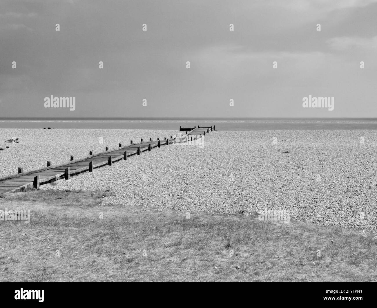 Image monochrome d'un chemin en bois qui mène à la plage de sable mer Banque D'Images