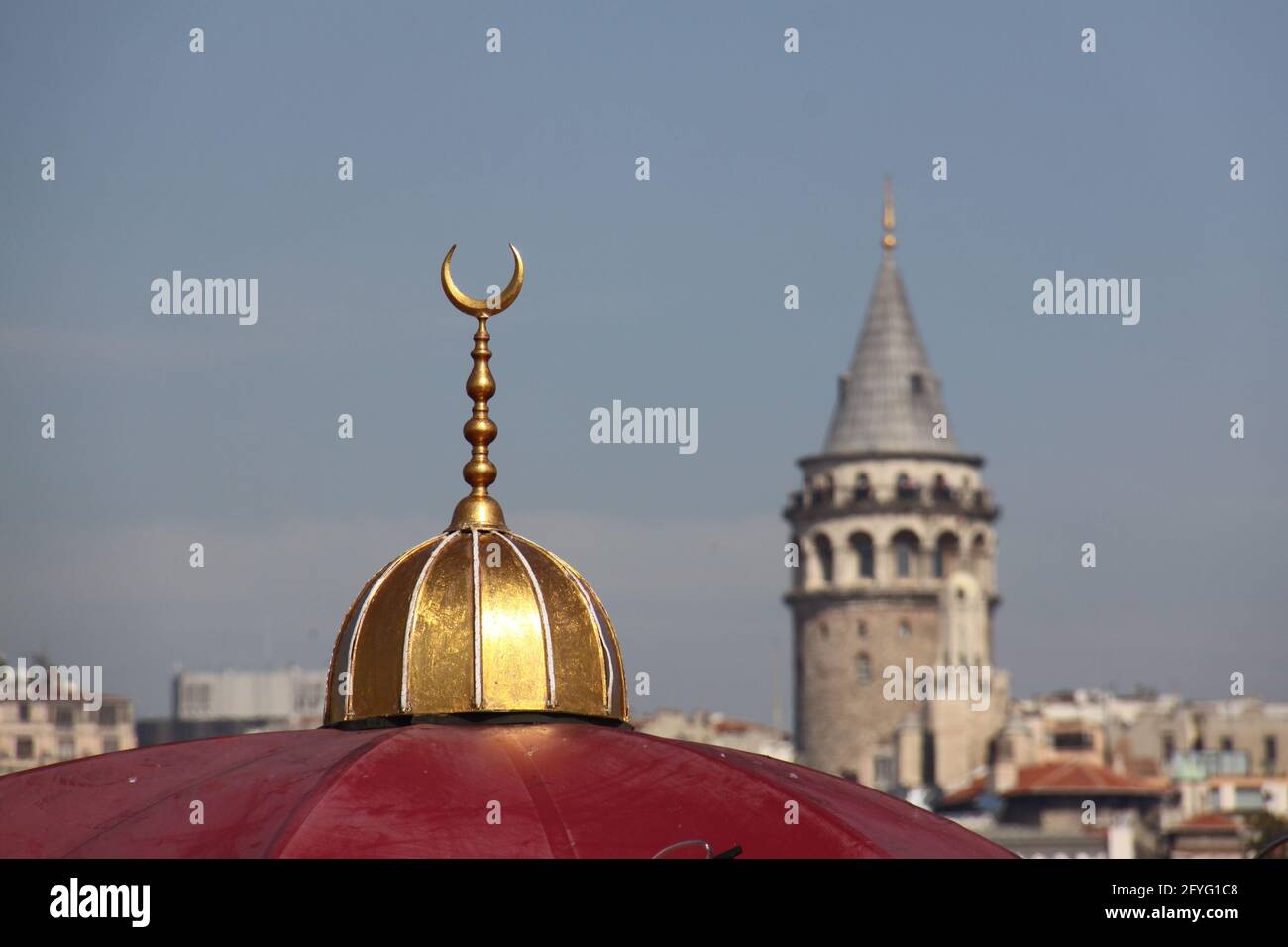 sommet d'un dôme rouge de la mosquée avec une demi-lune dorée sur le dessus et la tour de galata en arrière-plan Banque D'Images