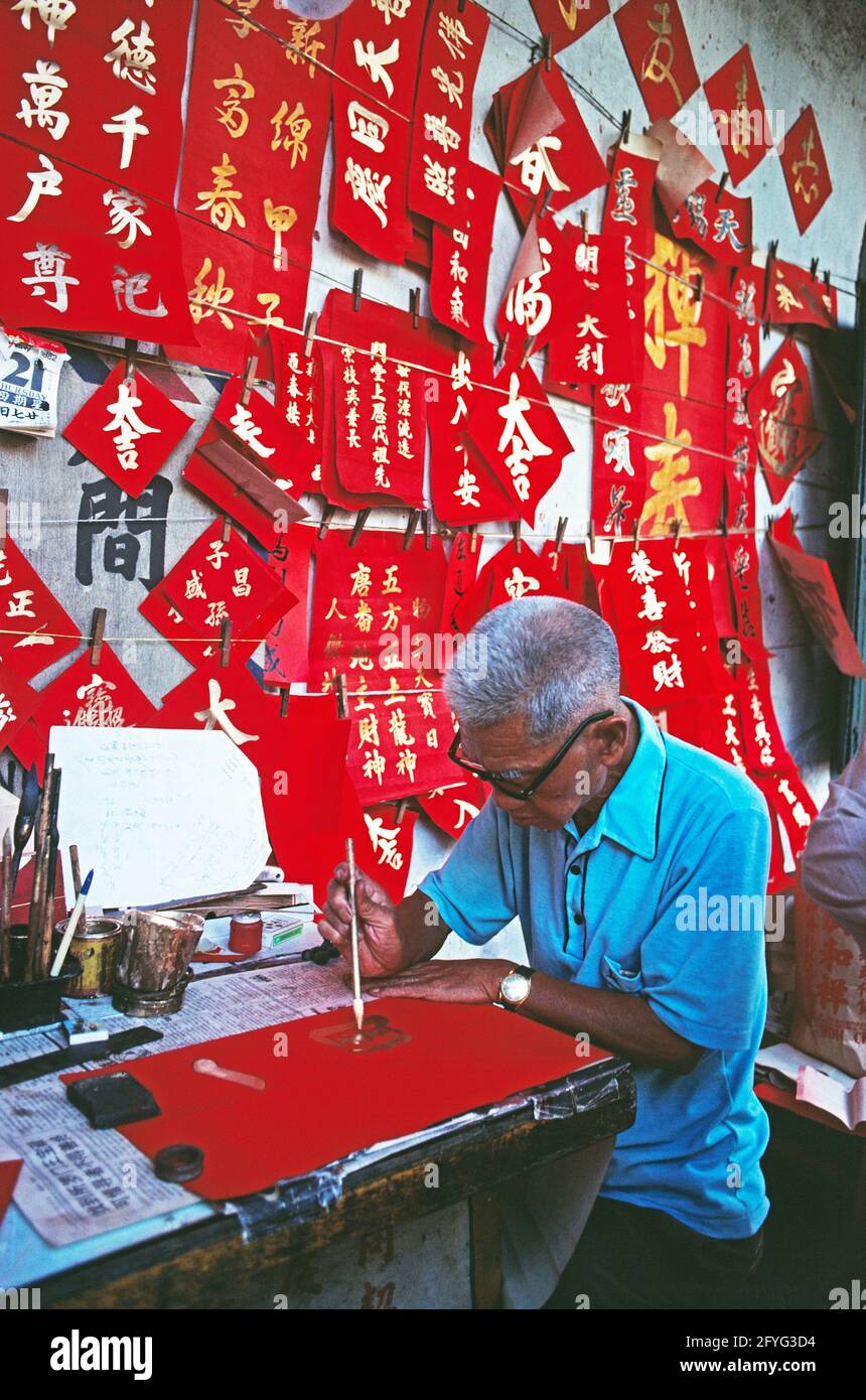 Singapour. Un vieil homme peint des signes calligraphiques pour les célébrations du nouvel an chinois. Banque D'Images