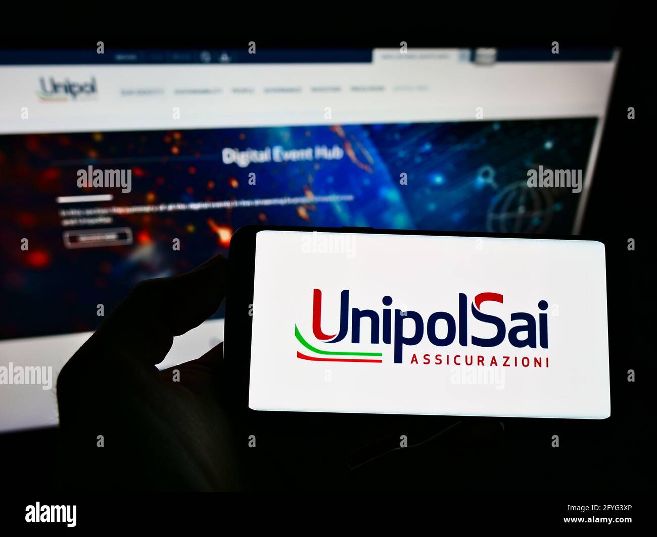Personne tenant un téléphone portable avec le logo de la société italienne UnipolSai Assicurazioni spa sur l'écran devant le site Web d'affaires. Mise au point sur l'affichage du téléphone. Banque D'Images