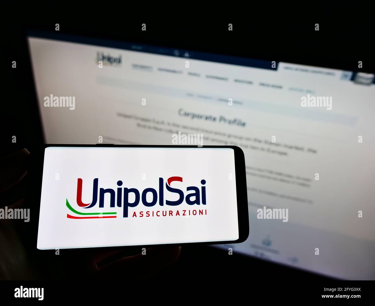 Personne tenant un téléphone portable avec le logo d'entreprise de la société italienne UnipolSai Assicurazioni S.p.A. à l'écran en face de la page web. Mise au point sur l'affichage du téléphone. Banque D'Images