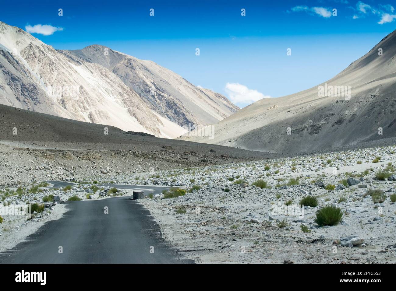 Une route en béton vers de belles montagnes rocheuses et ciel bleu avec des sommets de l'Himalaya, Leh, Ladakh, Jammu et Cachemire, Inde Banque D'Images