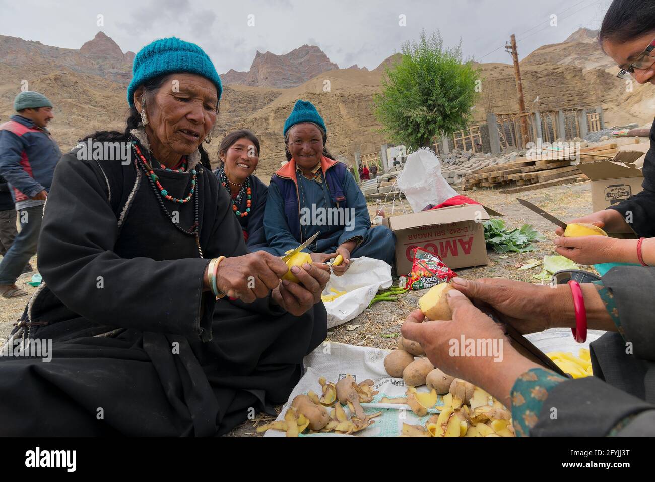 Mulbekh, Ladakh, Inde - 2 septembre 2014 : les femmes tribales ladakhi souriantes dans des robes traditionnelles coupent des pommes de terre pour préparer la nourriture pour le festival Banque D'Images