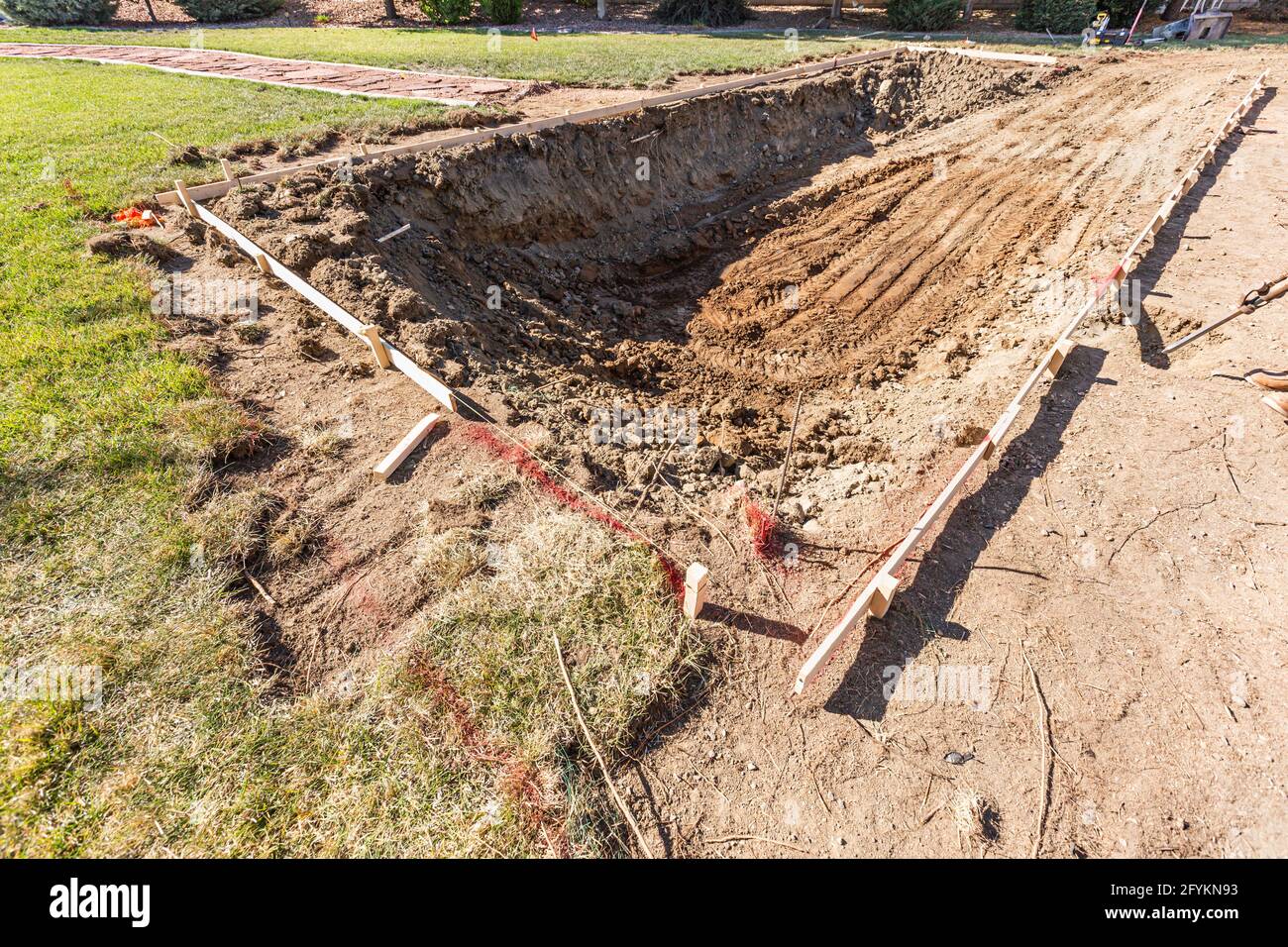 Trou fraîchement creusé dans la cour avant de se préparer à l'installation de la piscine. Banque D'Images