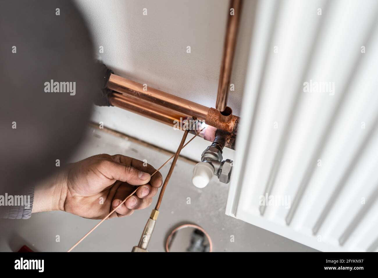 Un travailleur industriel inconnu est plombier avec soudage de tuyaux en  cuivre de chauffage central utilisation d'un chalumeau ou d'un chalumeau  sur le mur de la maison bâtiment ou appartement Photo Stock -