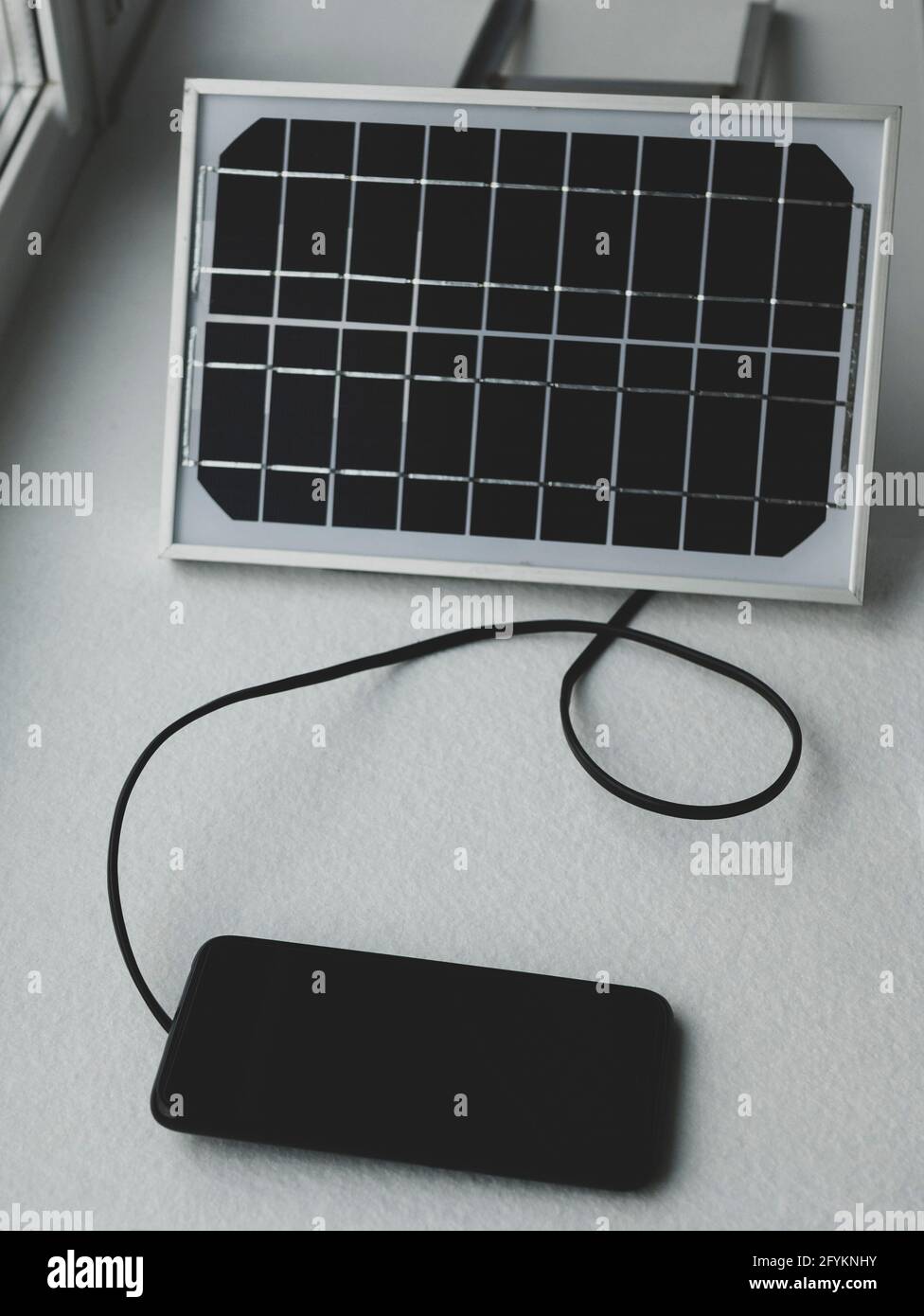 Le panneau solaire portable sur le rebord de la fenêtre génère de l'énergie  et recharge le smartphone. Autres sources d'énergie Photo Stock - Alamy