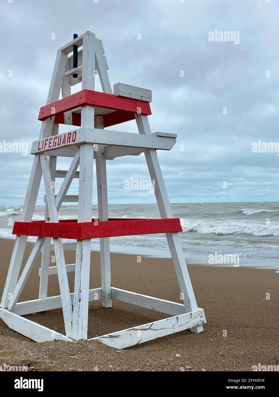 Chaise de maître nageur vide sur Tower Beach, le long de la côte de l'Illinois du lac Michigan, lors d'une journée de tempête alors que les vagues s'écrasont le long de la rive en arrière-plan. Banque D'Images