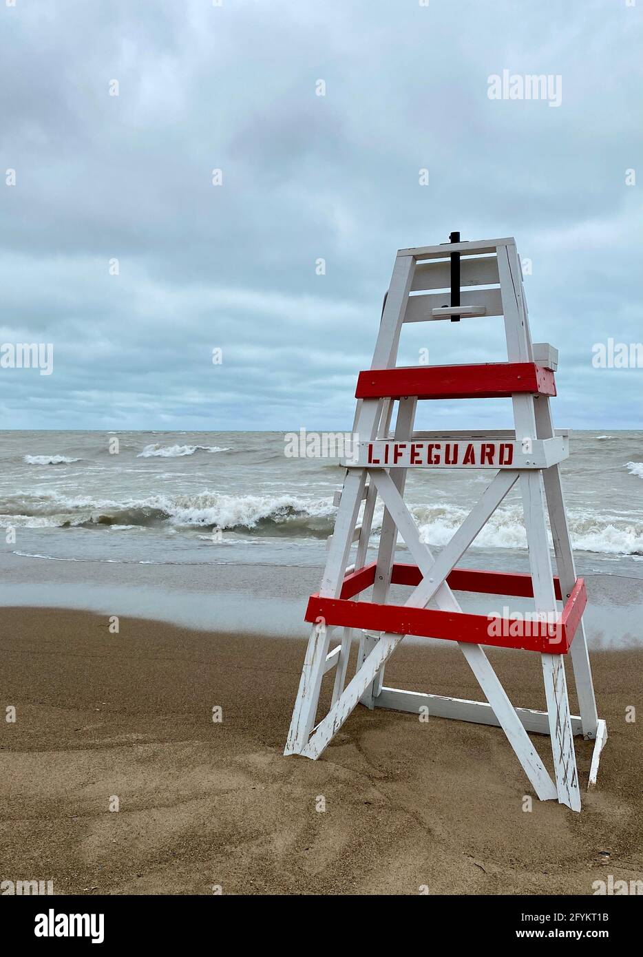Chaise de maître nageur vide sur Tower Beach, le long de la côte de l'Illinois du lac Michigan, lors d'une journée de tempête alors que les vagues s'écrasont le long de la rive en arrière-plan. Banque D'Images