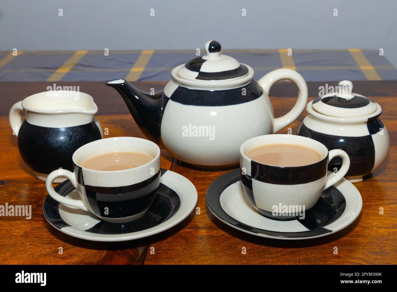 Théière avec tasse et soucoupe au design noir et blanc sur une table en bois Banque D'Images