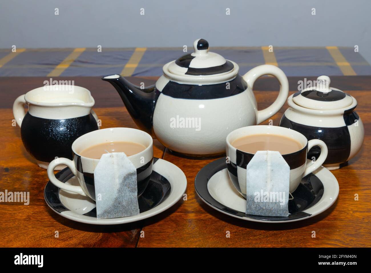 Théière avec tasse et soucoupe au design noir et blanc sur une table en bois Banque D'Images