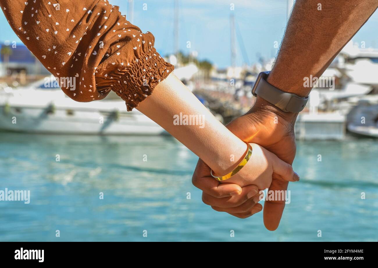 Gros plan des mains d'un couple multiethnique tenant les mains d'un bracelet et d'une montre. Scène d'amour Banque D'Images