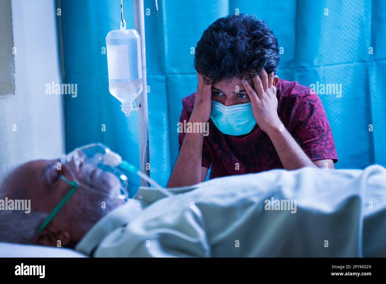 Inquiet stressé jeune homme à cause de son père covid 19 infection et respiration sur masque d'oxygène du ventilateur à l'hôpital - le concept de la maladie mentale Banque D'Images