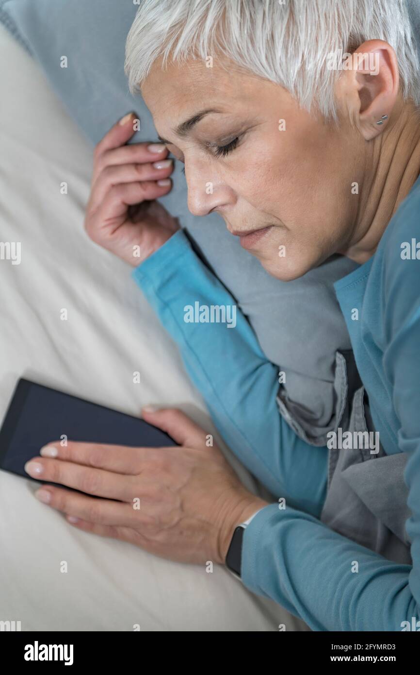 Femme dormant avec un smartphone Banque D'Images