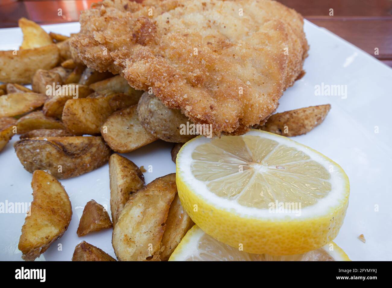 Feldkirch, Autriche - 26 juillet 2020 : steak de cordon bleu pané servi avec des pommes de terre au four et du citron Banque D'Images