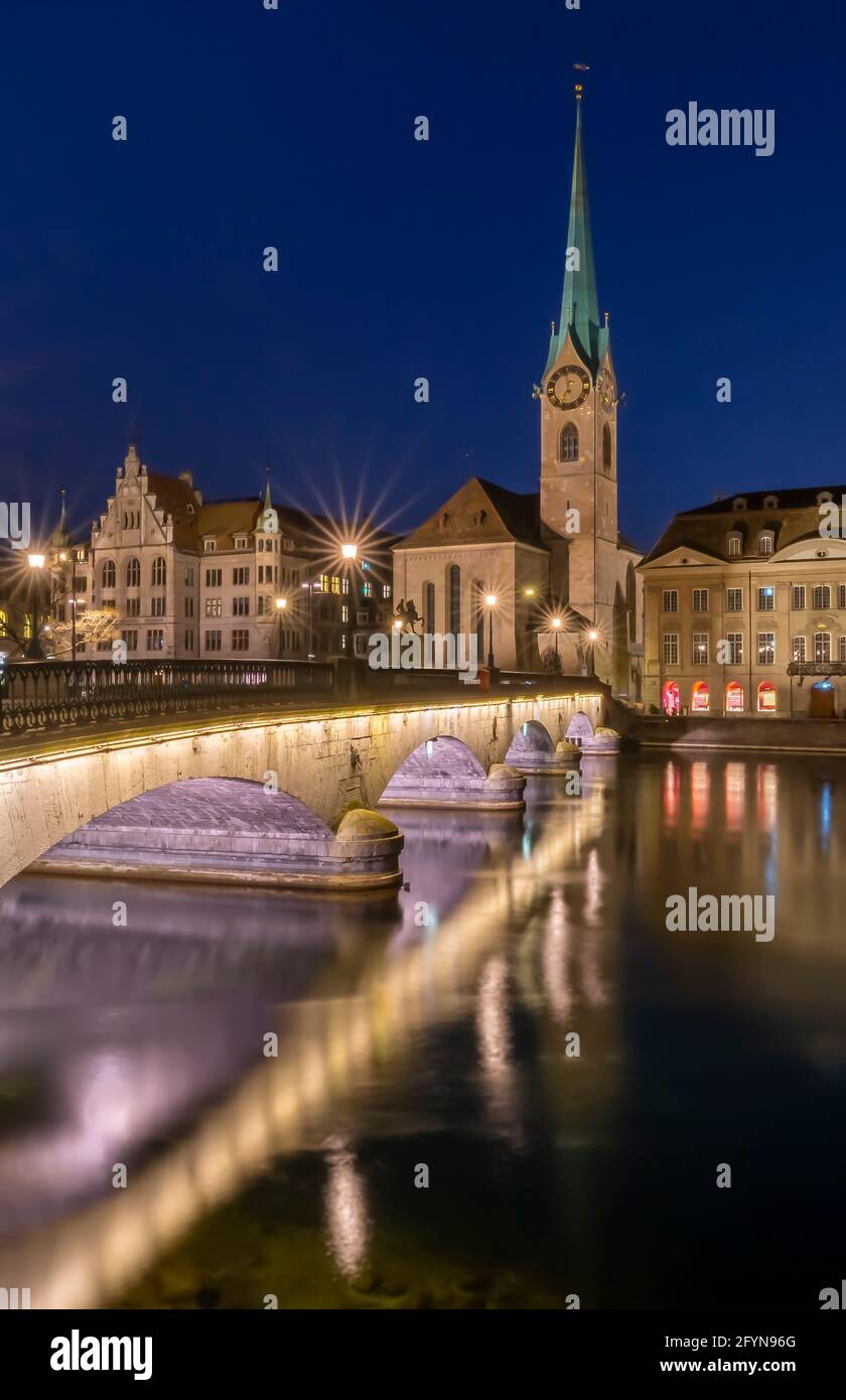 Vue sur le pont et l'eau du lac à l'église Fraumunster à Zurich, Suisse, à l'heure bleue de la nuit Banque D'Images