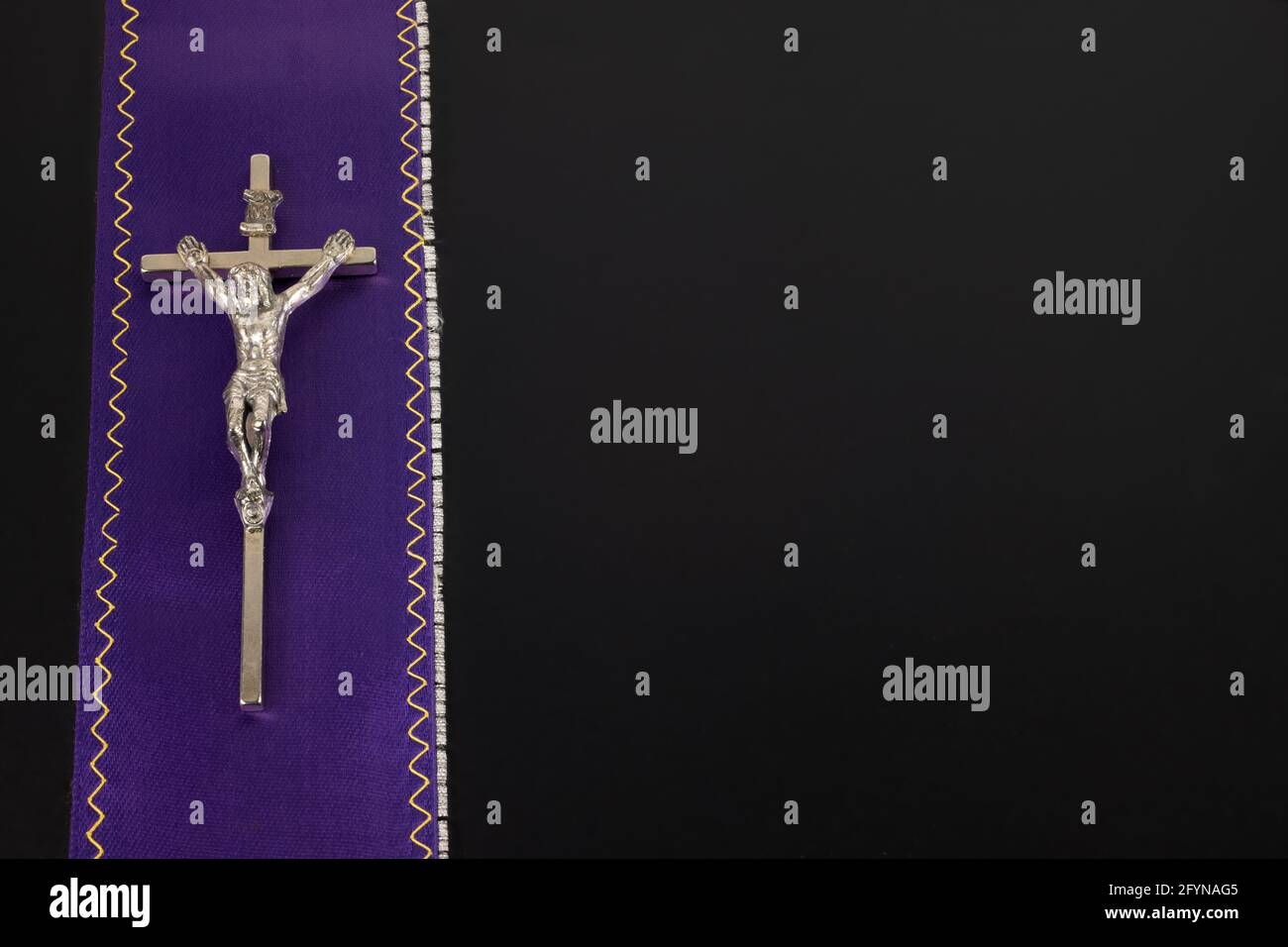 Taupe de prêtre violet avec une croix métallique sur un arrière-plan noir Banque D'Images
