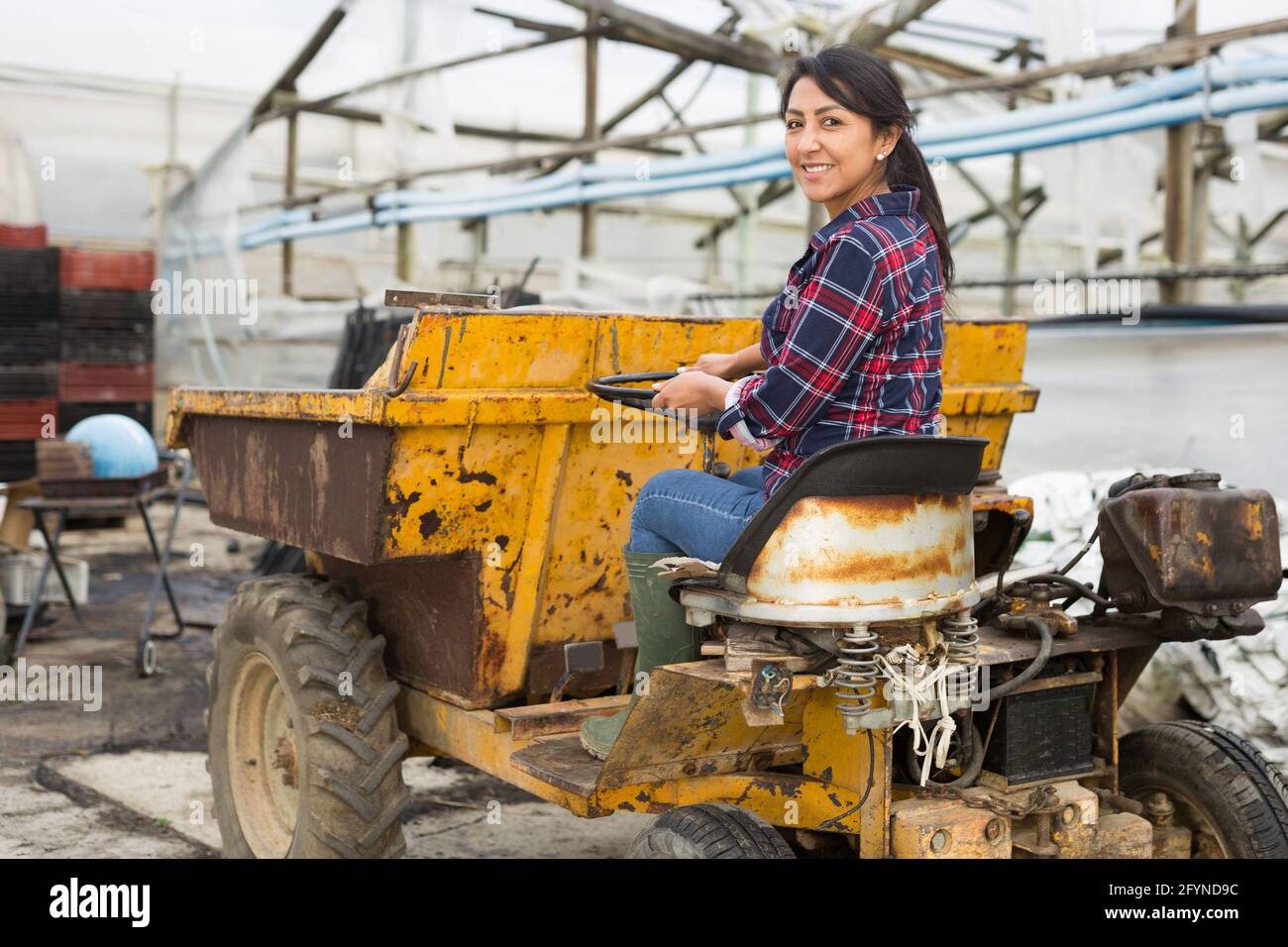 Une femme paysanne latino-américaine travaillant dans une entreprise qui conduit un mini-camion à benne pour jeter les mauvaises herbes. Banque D'Images