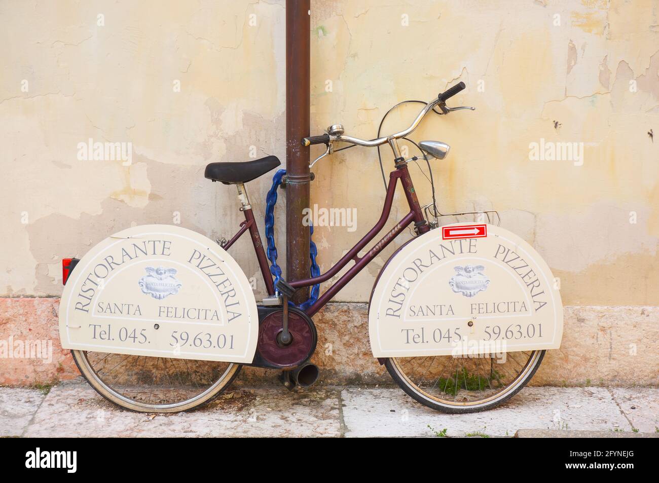 VÉRONE, ITALIE - 27 avril 2016: Vélo avec des signes de Ristorante Pizzeria Santa Felicita verrouillé sur un tuyau Banque D'Images