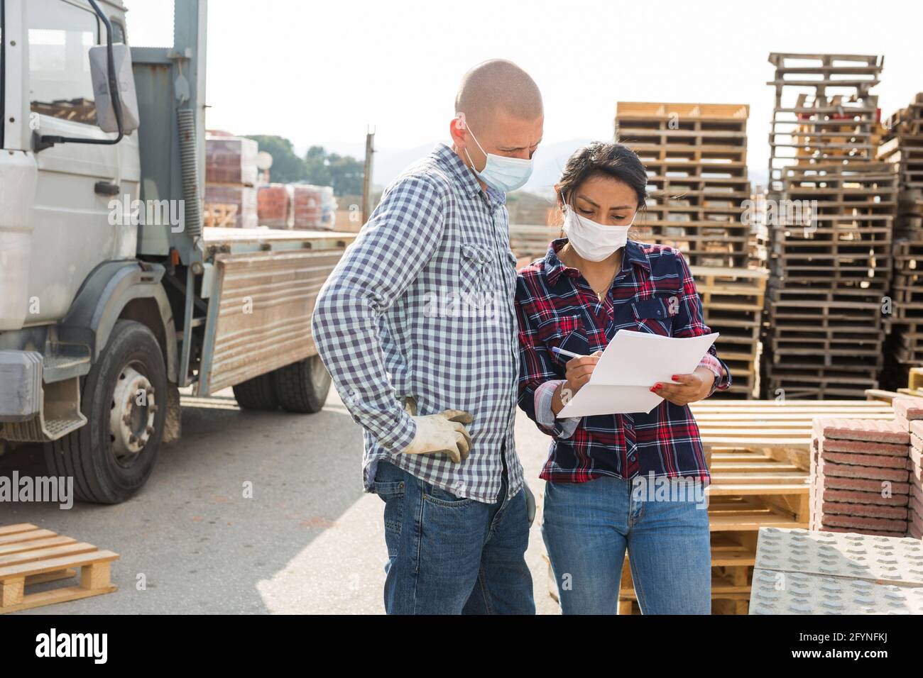 Homme ouvrier et femme préparateur de commande dans le visage masques de collecte ordre dans l'entrepôt de matériaux de construction Banque D'Images