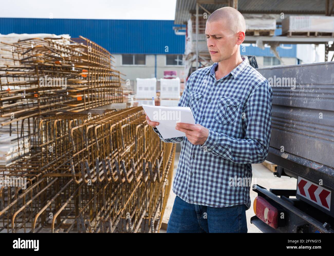 Jeune homme préparateur de commande avec des papiers de collecte de produits dans l'entrepôt de matériaux de construction Banque D'Images