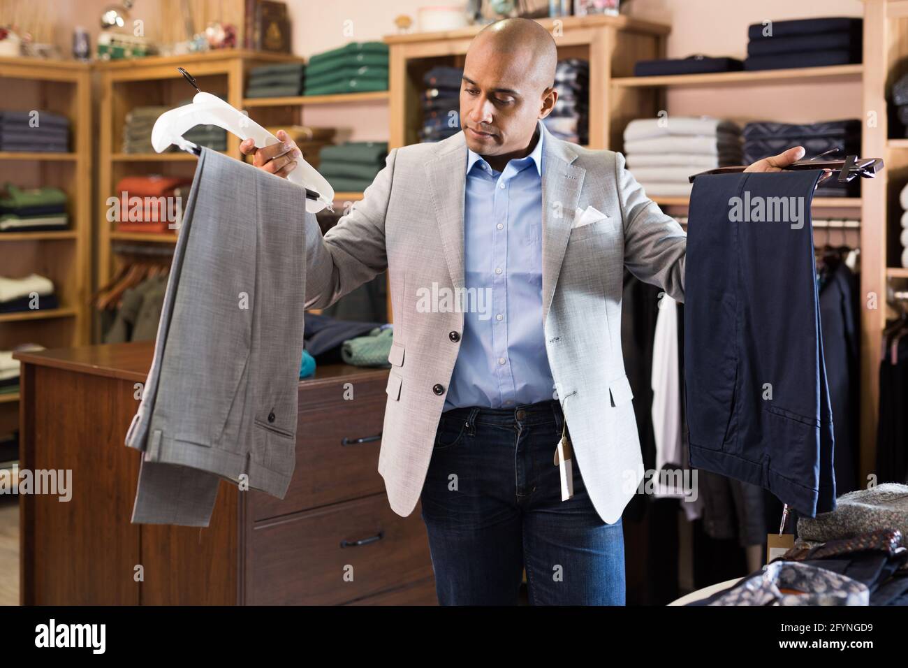 Portrait d un jeune homme adulte choisissant un pantalon de costume a une nouvelle veste dans le magasin de vetements Photo Stock Alamy