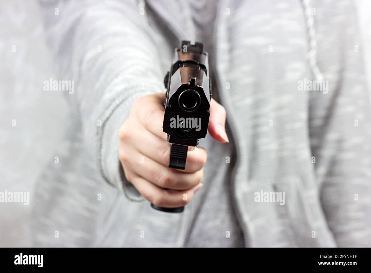 Femme caucasienne main tenant une arme prête à tirer. Violence par armes à feu, crime et meurtre. Banque D'Images
