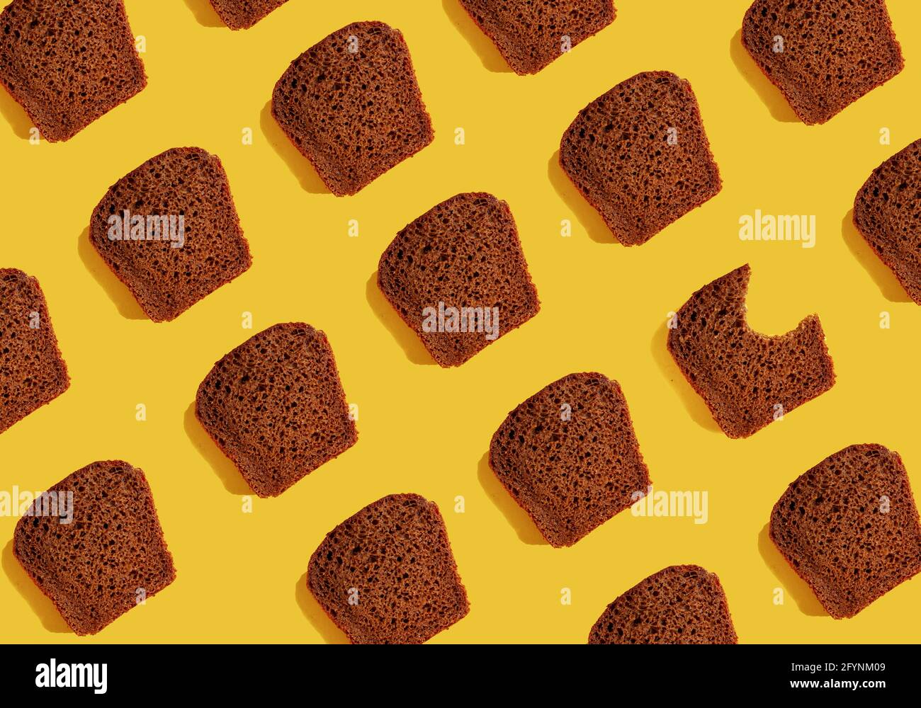 Motif de morceaux de pain de seigle foncé sur fond jaune. Modèle alimentaire. Banque D'Images
