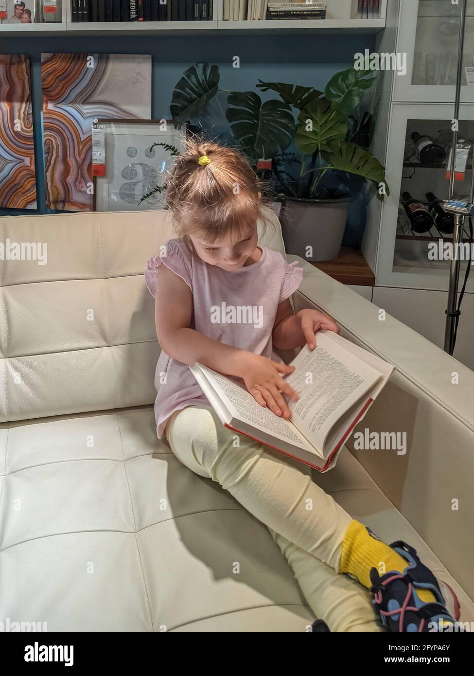 05.23.2021 Ikea, Moscou, Russie. Enfant fille assise sur le canapé dans le magasin et lisant un livre. Achat de meubles Banque D'Images