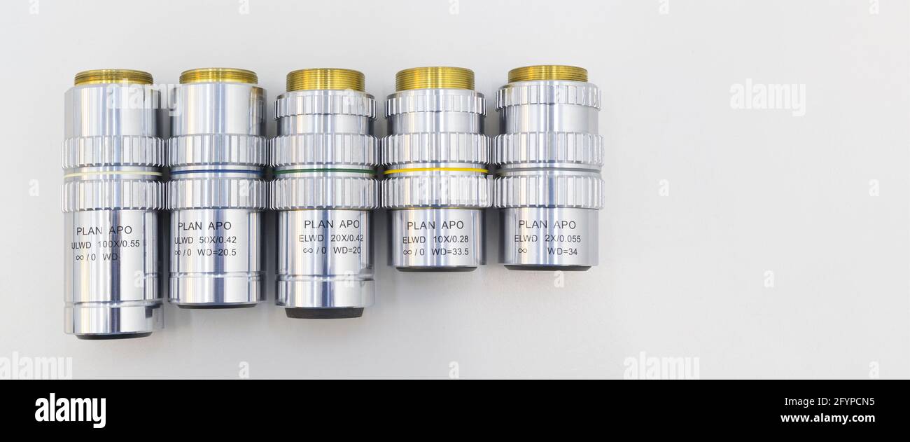 Beaucoup d'objectifs différents de l'agrandissement sur un fond blanc. Gros plan des objectifs du microscope. Banque D'Images
