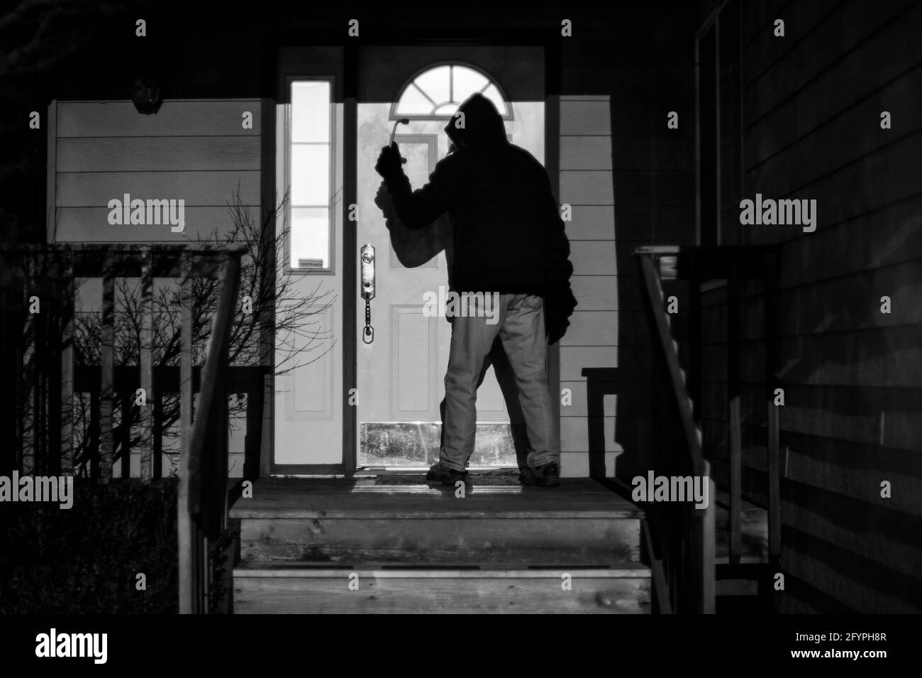 Cambrioleur se brisant à la maison la nuit debout à la porte d'entrée Banque D'Images