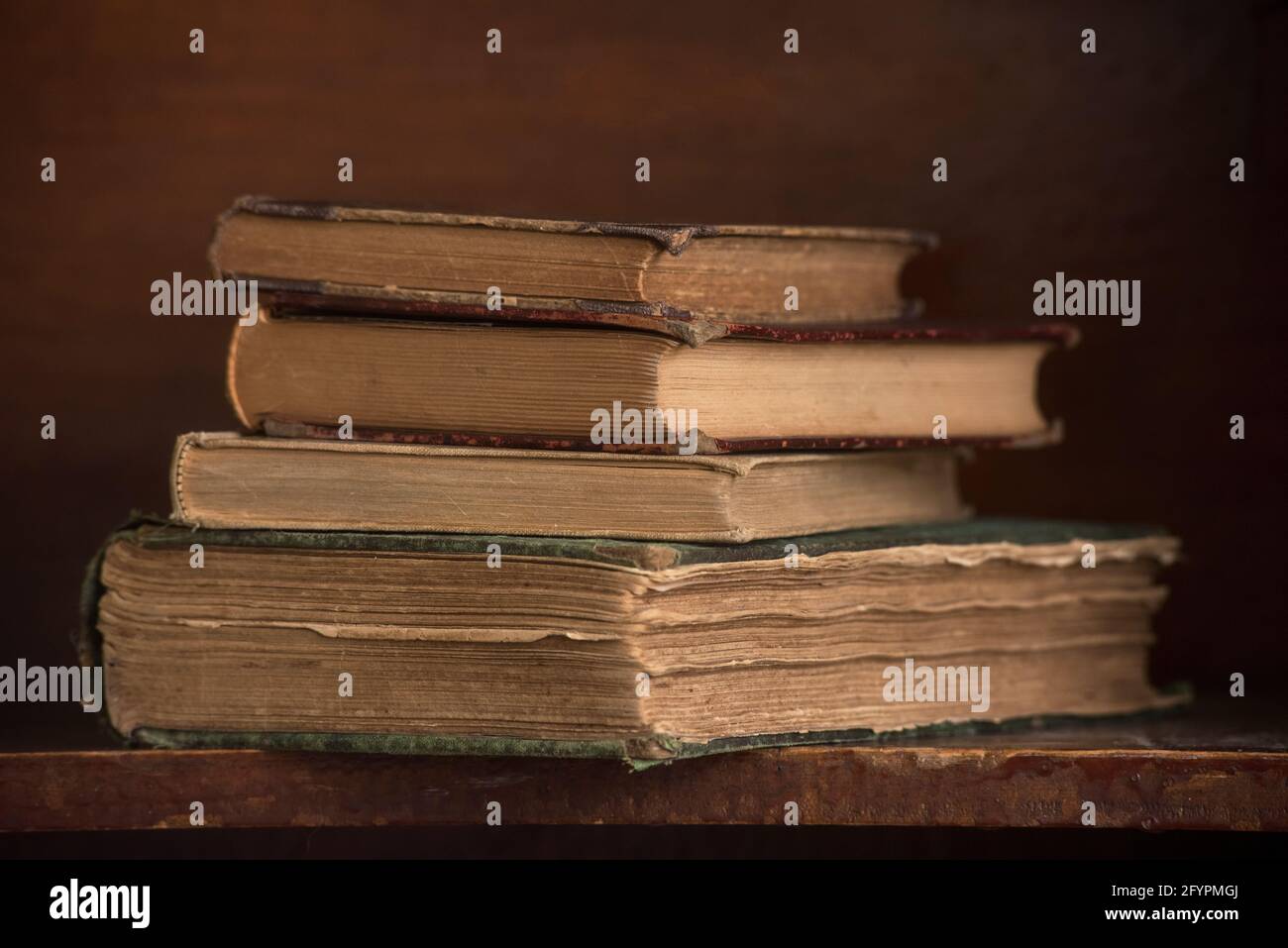 Un groupe de livres anciens sont empilés sur une étagère de livres dans une vie encore. Banque D'Images