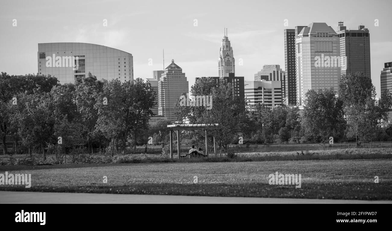Couple à une date à Columbus Ohio dans un parc balançant en regardant le paysage de la ville noir et blanc Banque D'Images