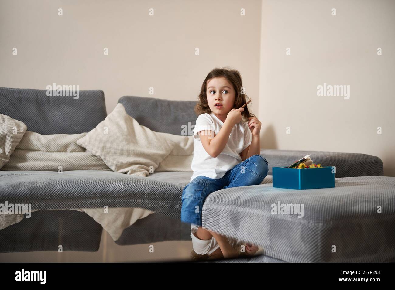 Jolie petite fille peignant ses cheveux avec un peigne en bois tout en  étant assis sur le canapé dans le salon. Concept d'hygiène du matin Photo  Stock - Alamy