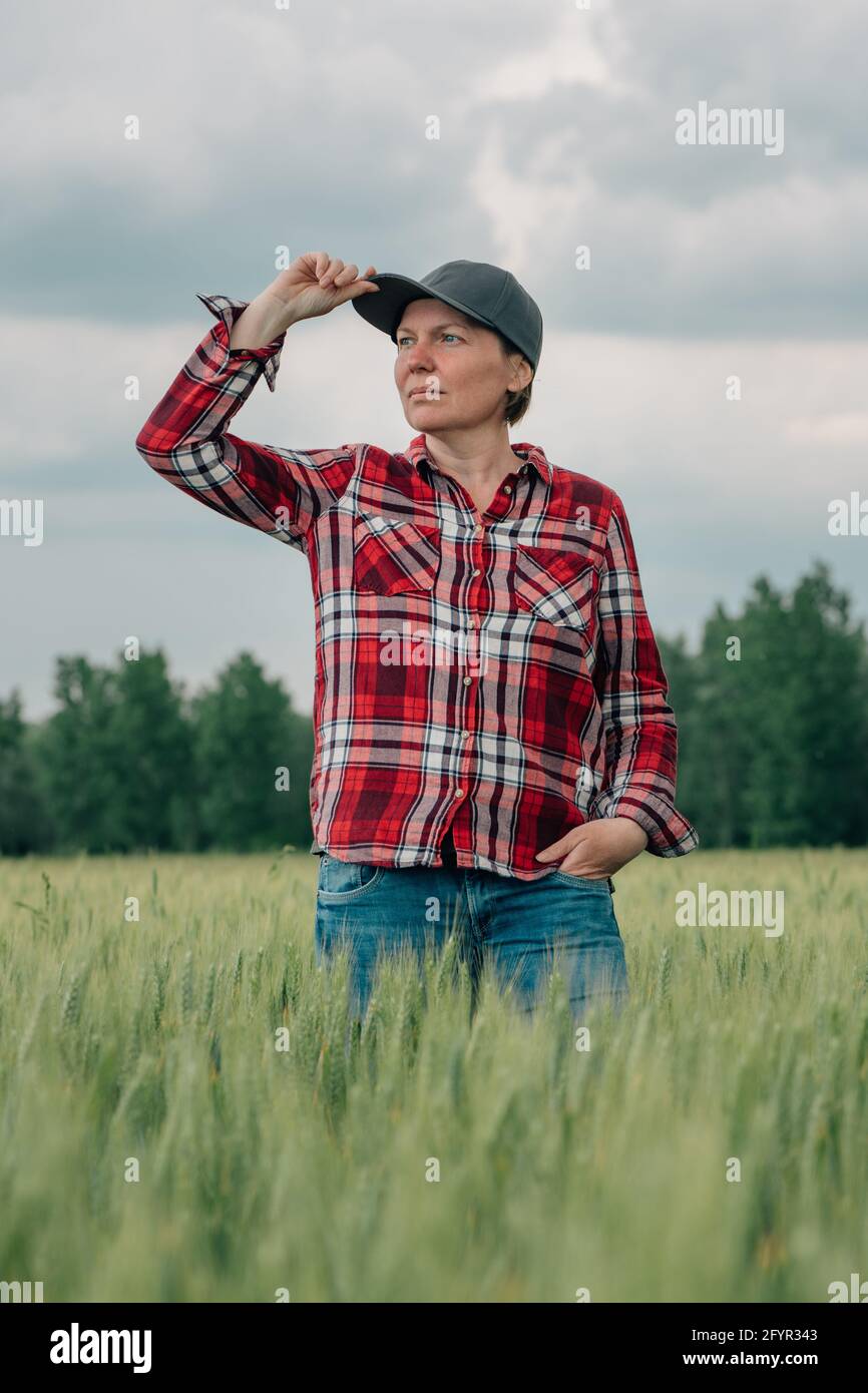 Agronome responsable de l'agriculteur de blé regardant son champ agricole de céréales cultivées, une travailleuse agricole posant sur les terres agricoles Banque D'Images