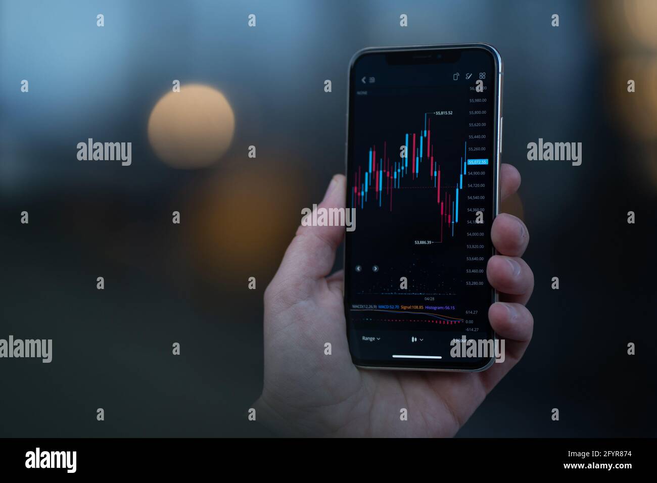 Trader regardant le téléphone mobile avec le tableau de stock à l'écran Banque D'Images