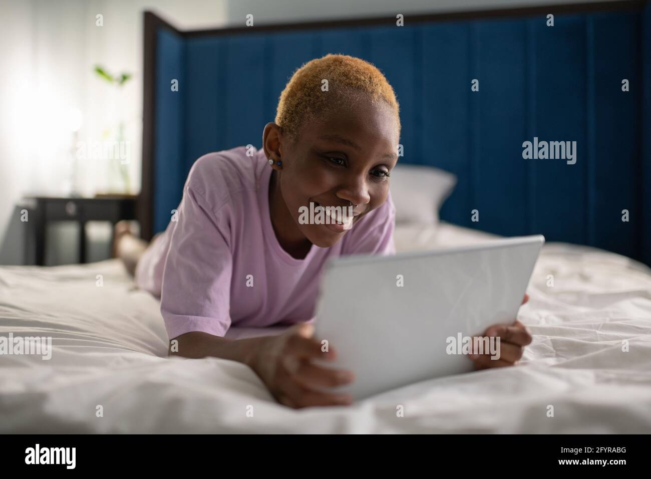 Jeune femme joyeuse utilisant une tablette dans la chambre Banque D'Images