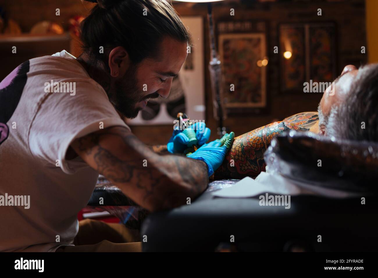 L'artiste de tatouage aime travailler sur le bras d'un client dans son studio. Banque D'Images