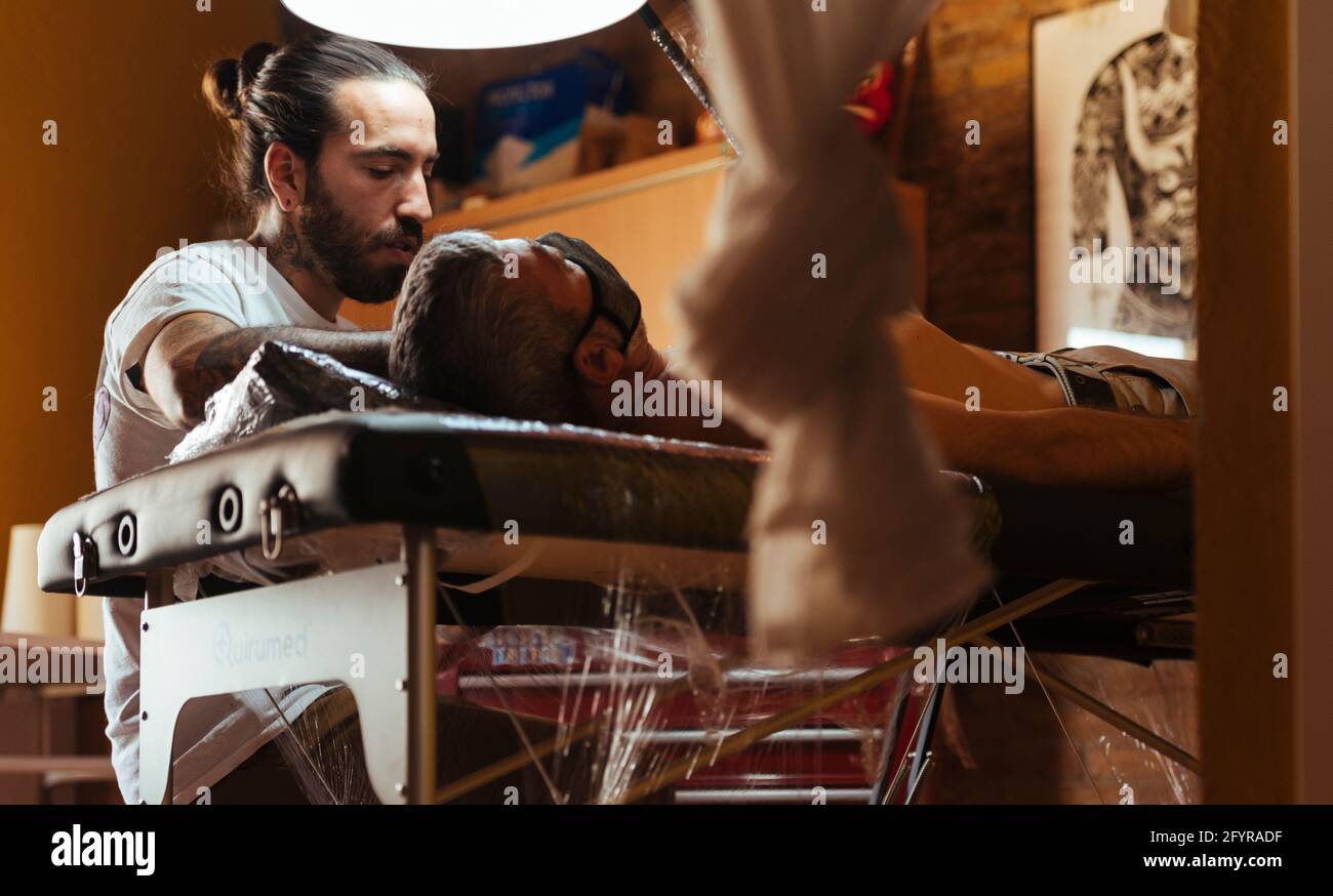 Voir sous de tatouage artiste travaillant avec un client dans son studio. Banque D'Images
