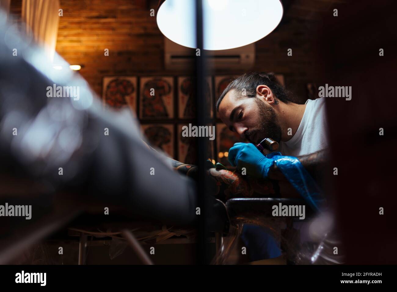Voir sous de tatouage artiste travaillant avec un client dans son studio. Banque D'Images