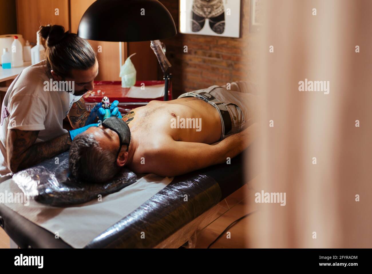 Tatouage artiste travaillant sur le bras d'un client dans son studio. Banque D'Images