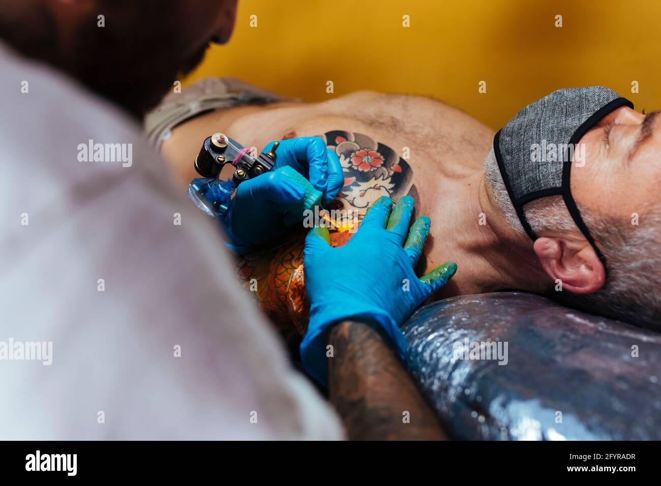 Gros plan des mains d'un artiste tatouant sur le bras d'un client. Banque D'Images