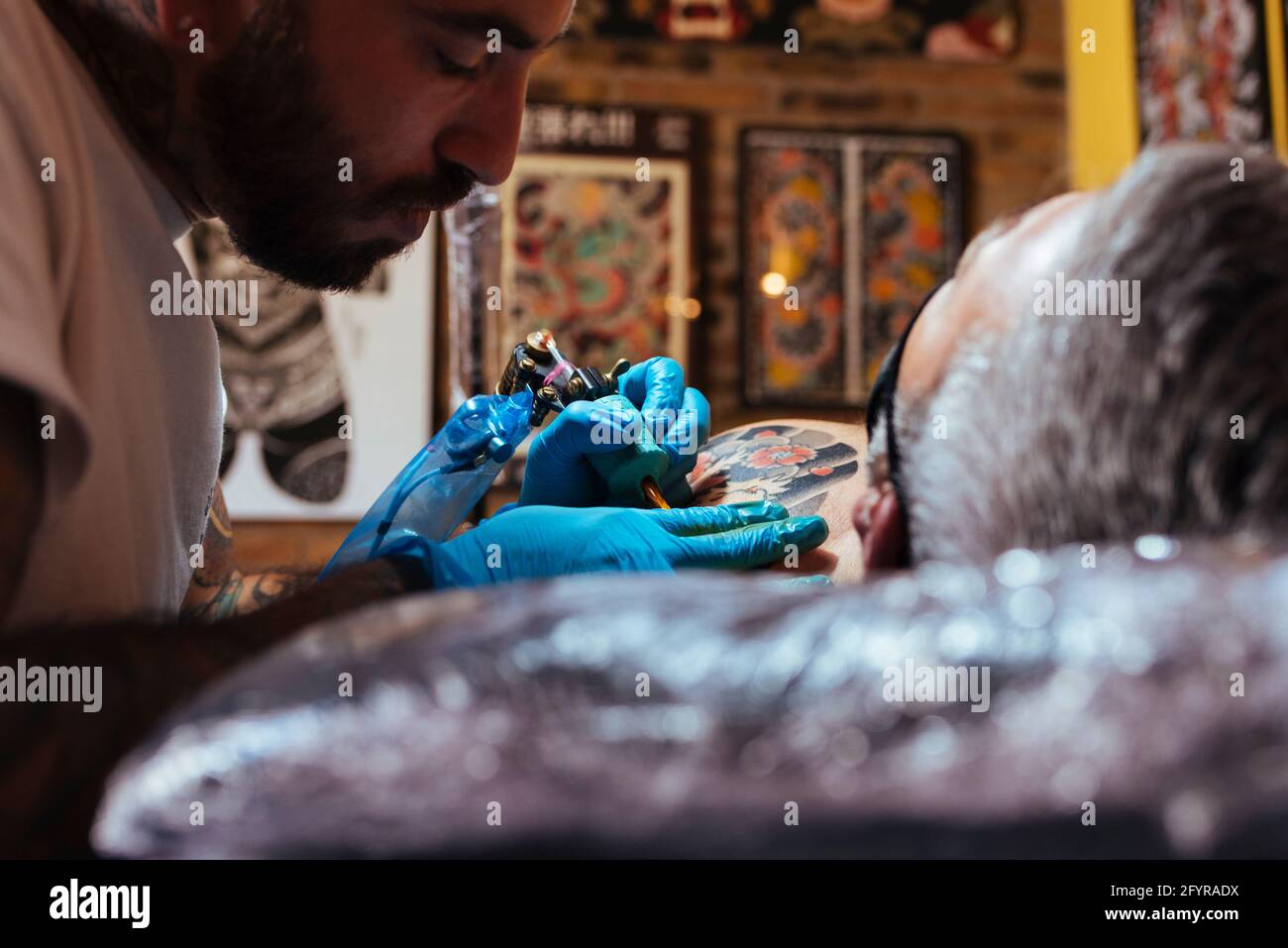 Gros plan d'un tatouage artiste travaillant sur le bras d'un client dans son studio. Banque D'Images