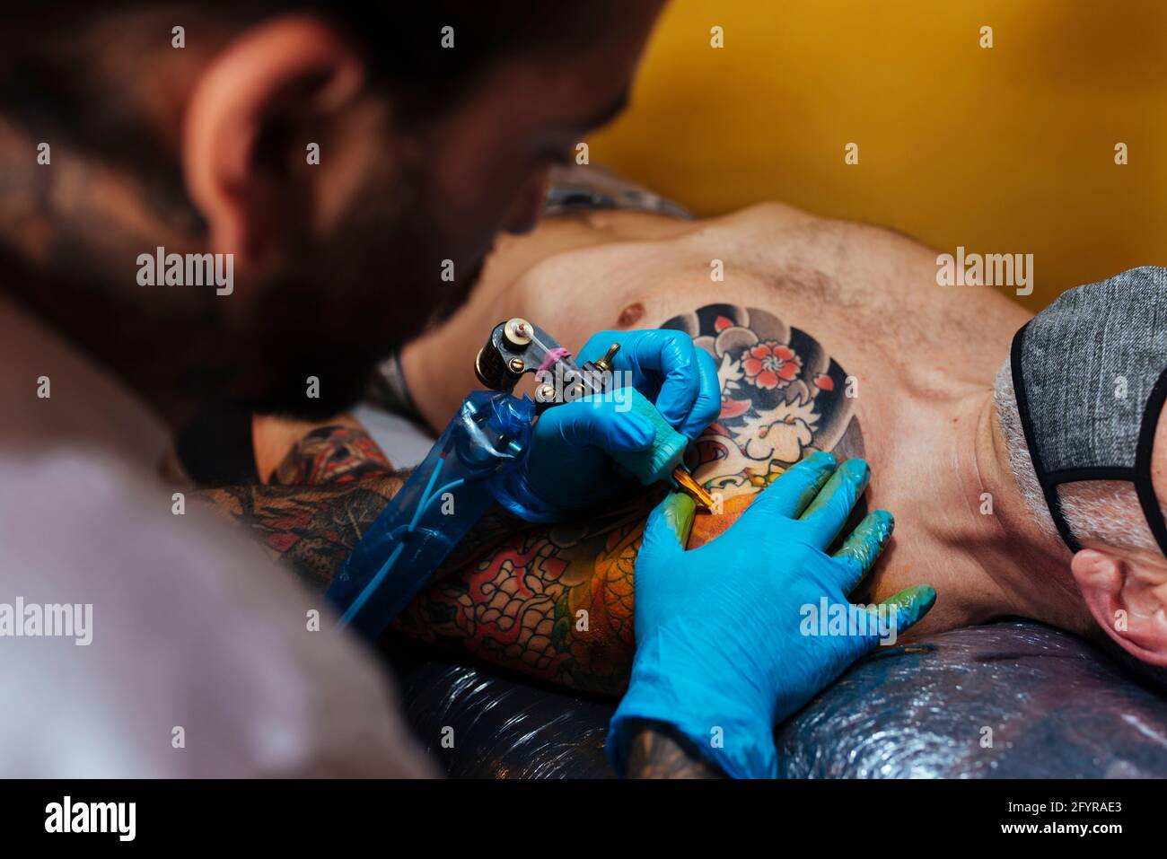 Gros plan des mains d'un artiste tatouant sur le bras d'un client. Banque D'Images