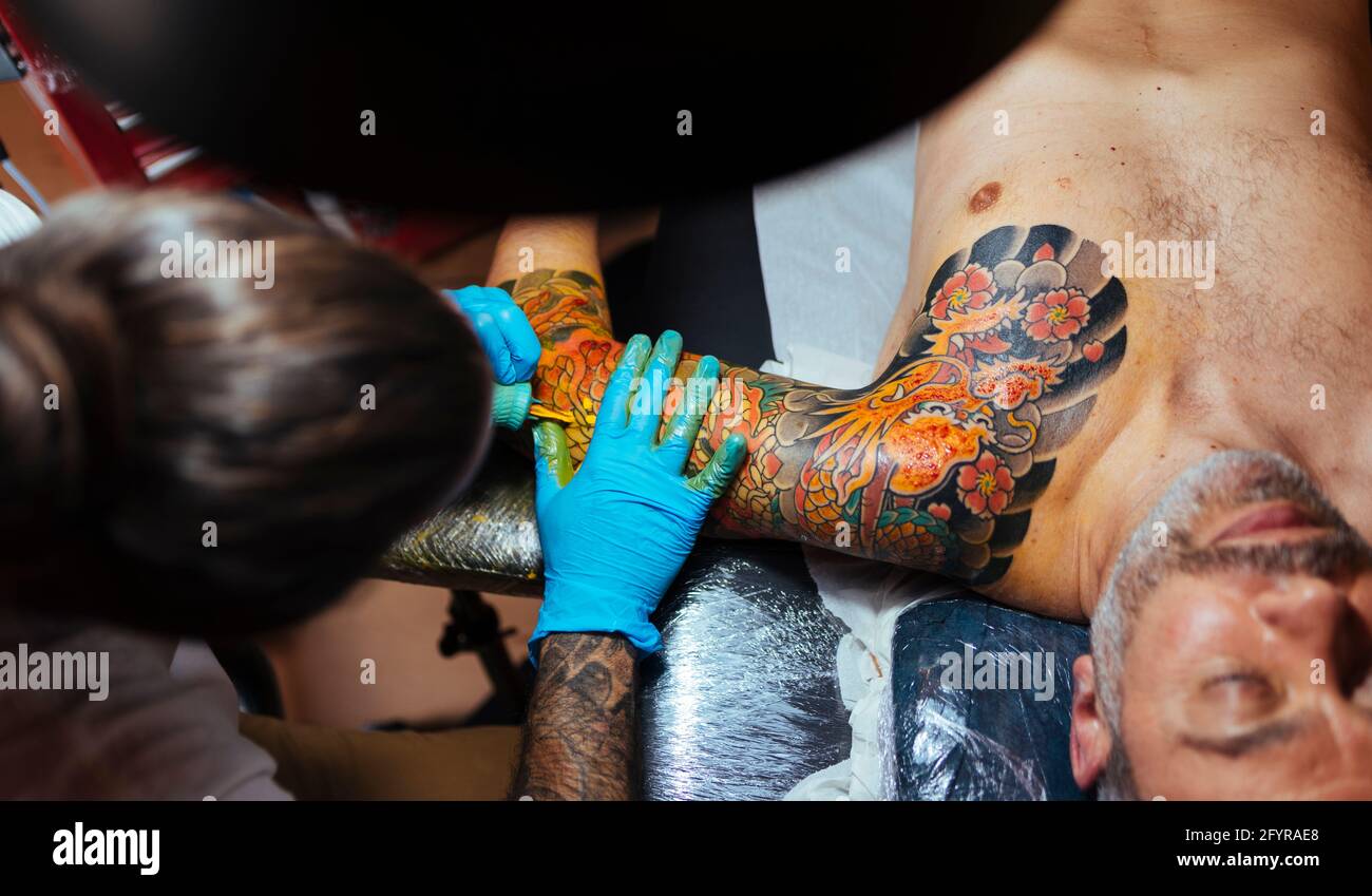 Vue aérienne d'un tatouage artiste travaillant sur le bras d'un client. Banque D'Images